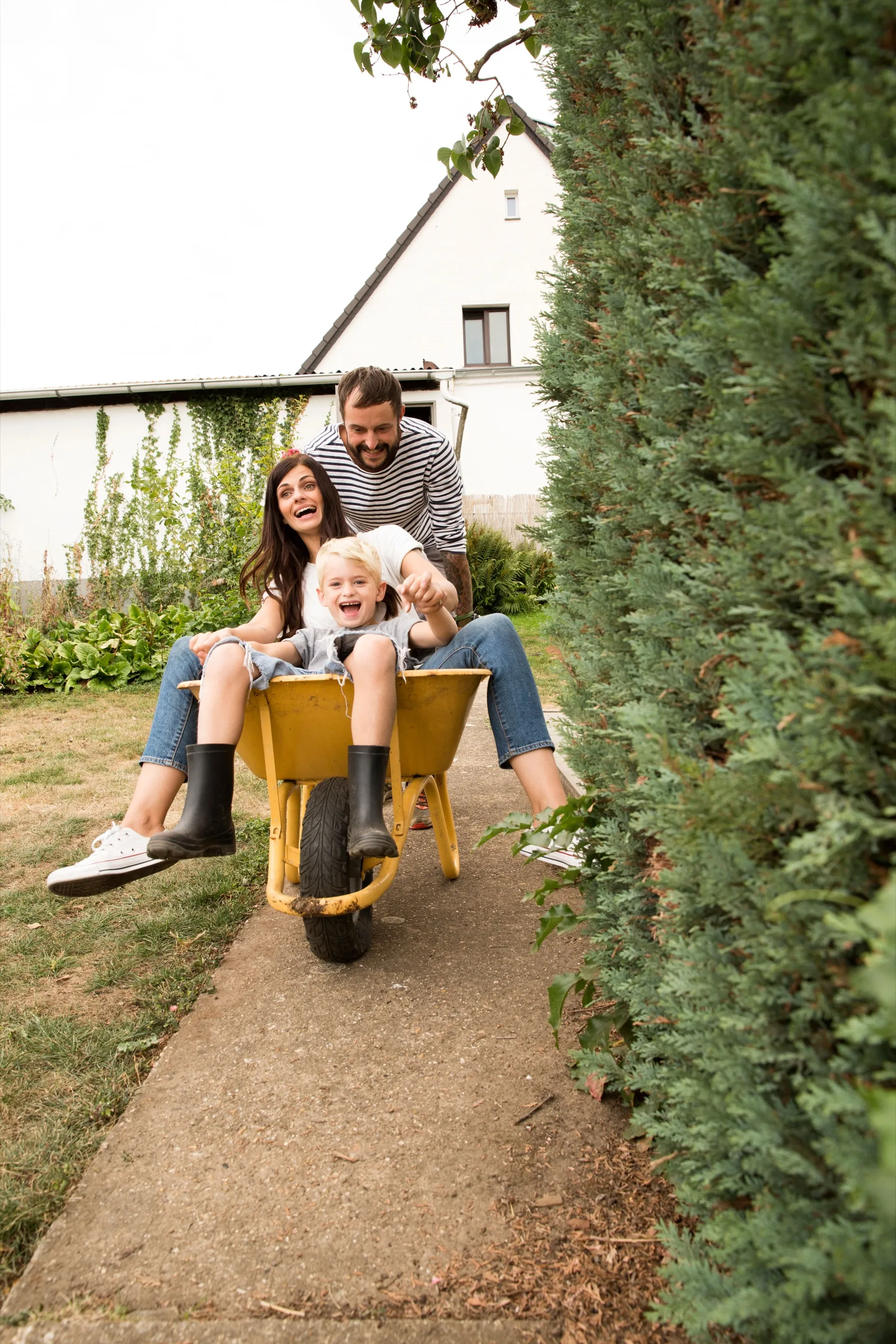 Family playing with a wheelbarrow in the yard